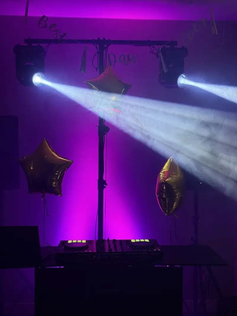 DJ booth with moving head lights and haze effects at a party