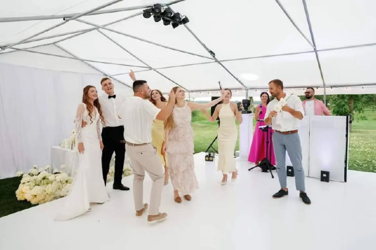 Wedding guests dancing under a tent with DJ and moving head lights