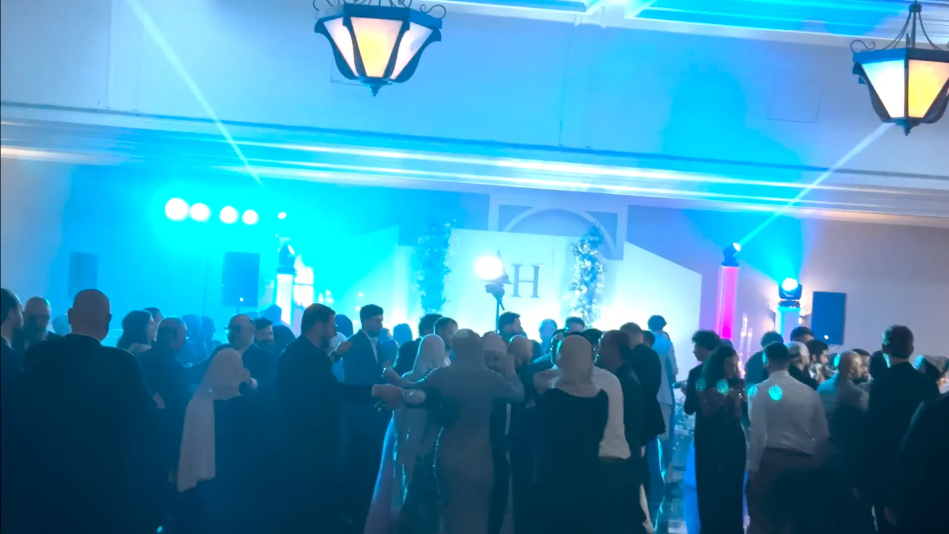 Packed dance floor with professional sound system and blue event lighting at a wedding reception in Minneapolis Minnesota